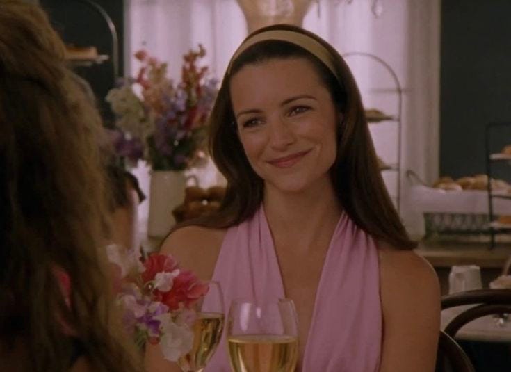 This may contain: a woman sitting at a table with two glasses of wine