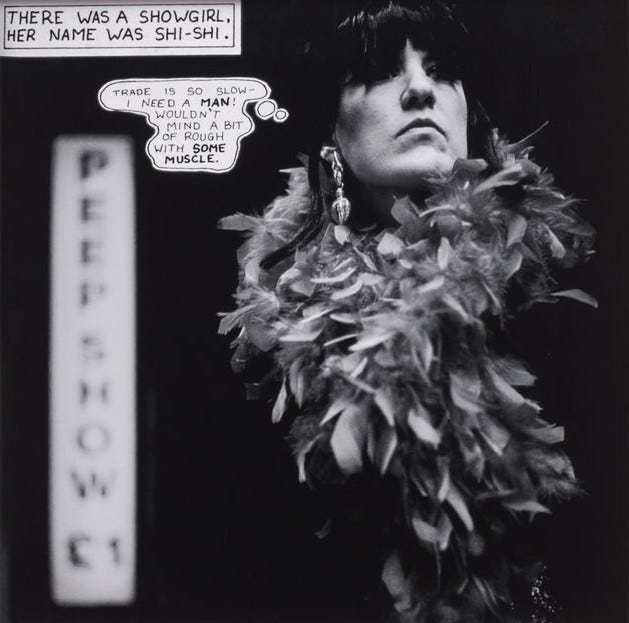 Black and white image of a woman with a stern expression, wearing a feather boa and large earrings. Text reads "There was a showgirl. Her name was Shi-Shi." A thought bubble says, "Trade is so slow. Need a man! Wouldn't mind a bit of rough with some muscle." A sign in the background reads "Peep Show." The tone is gritty and reflective. The woman has short black hair with bangs covering parts of her eyes. She looks to be wearing false eyelashes.