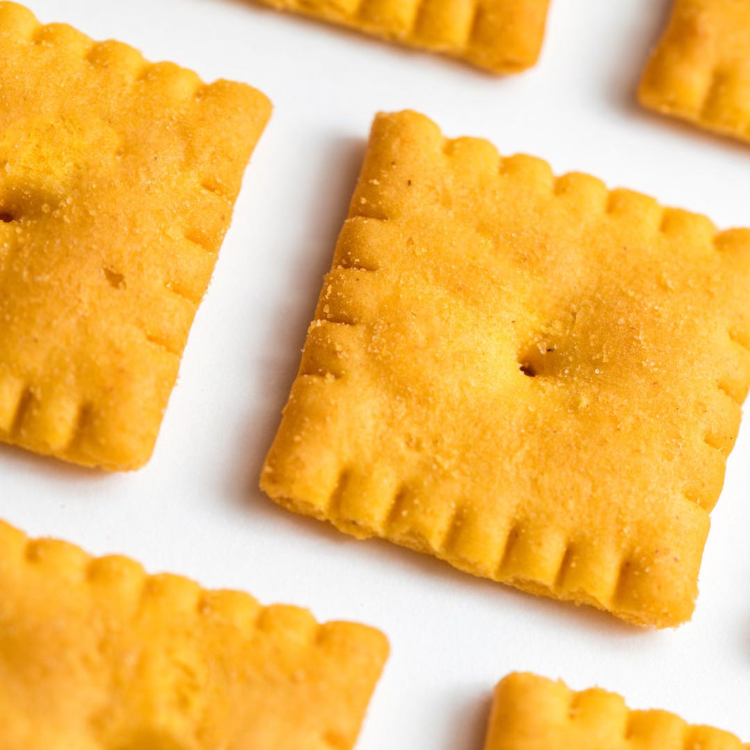 Square cheese crackers lined up at an angle against a white background Square cheese crackers lined up at an angle against a white background