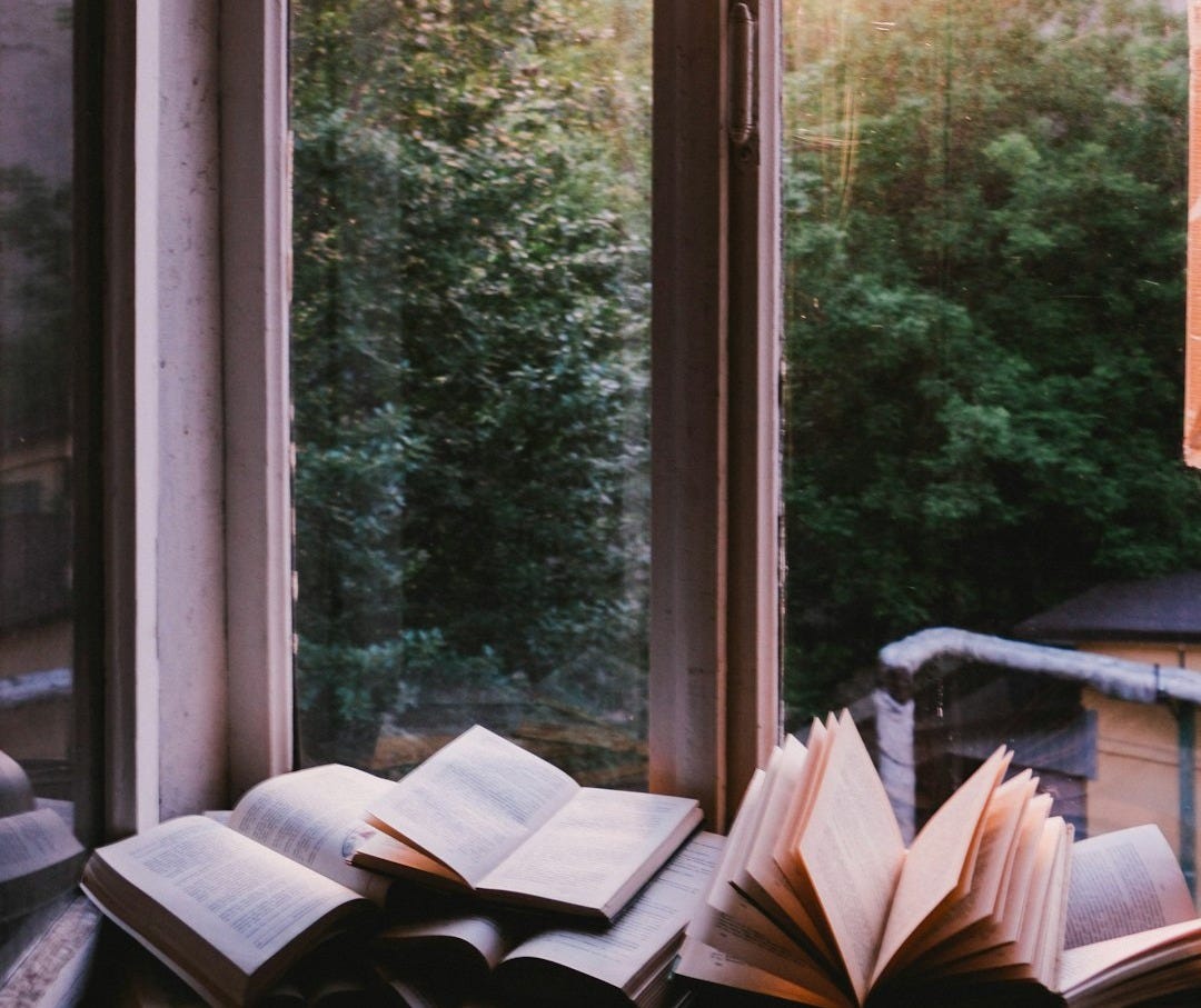 books beside window during sunset