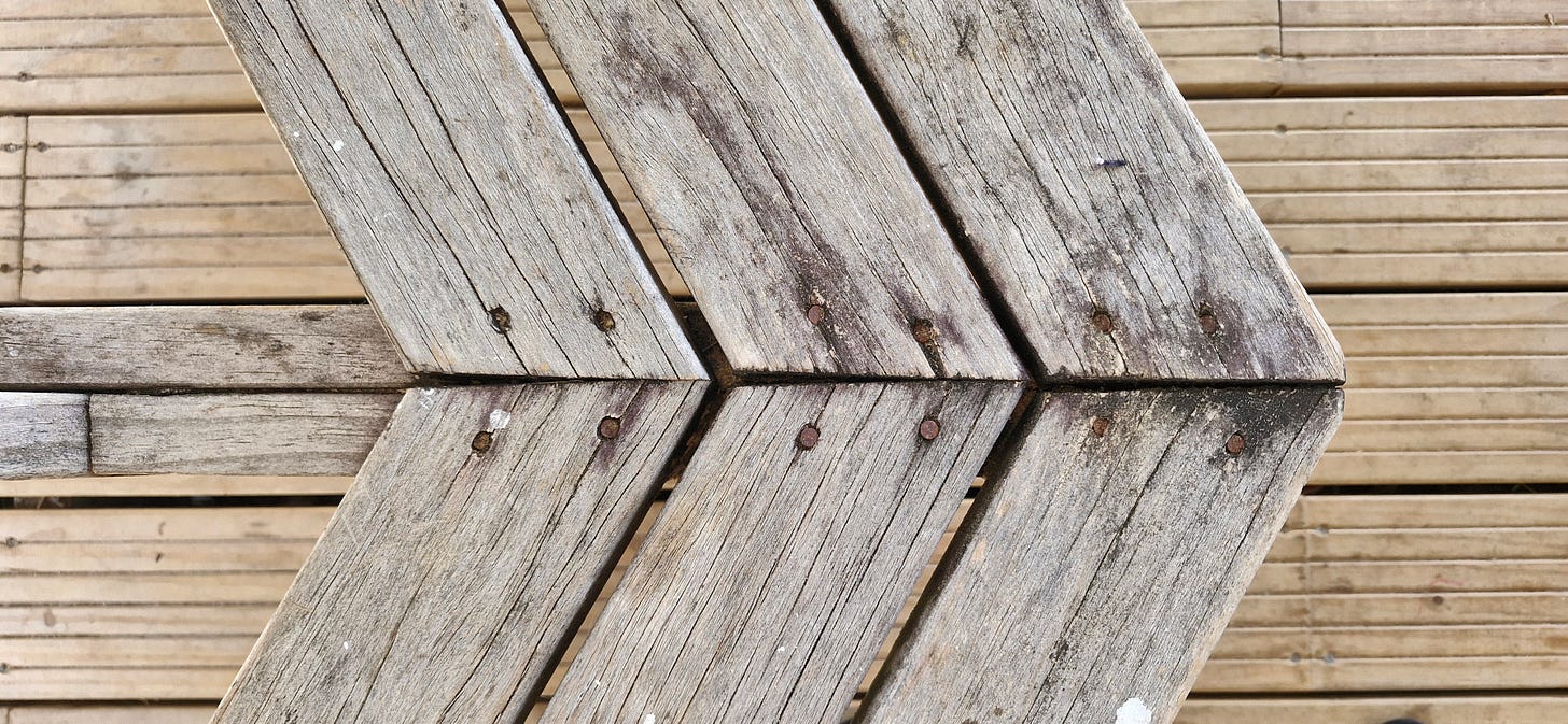 photo of a wood bench on a wood patio, the wood makes for an interesting pattern