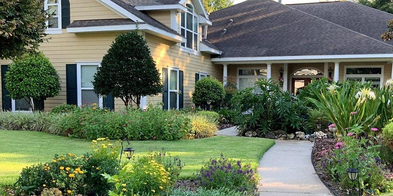 A yellow two story house with a landscaped yard