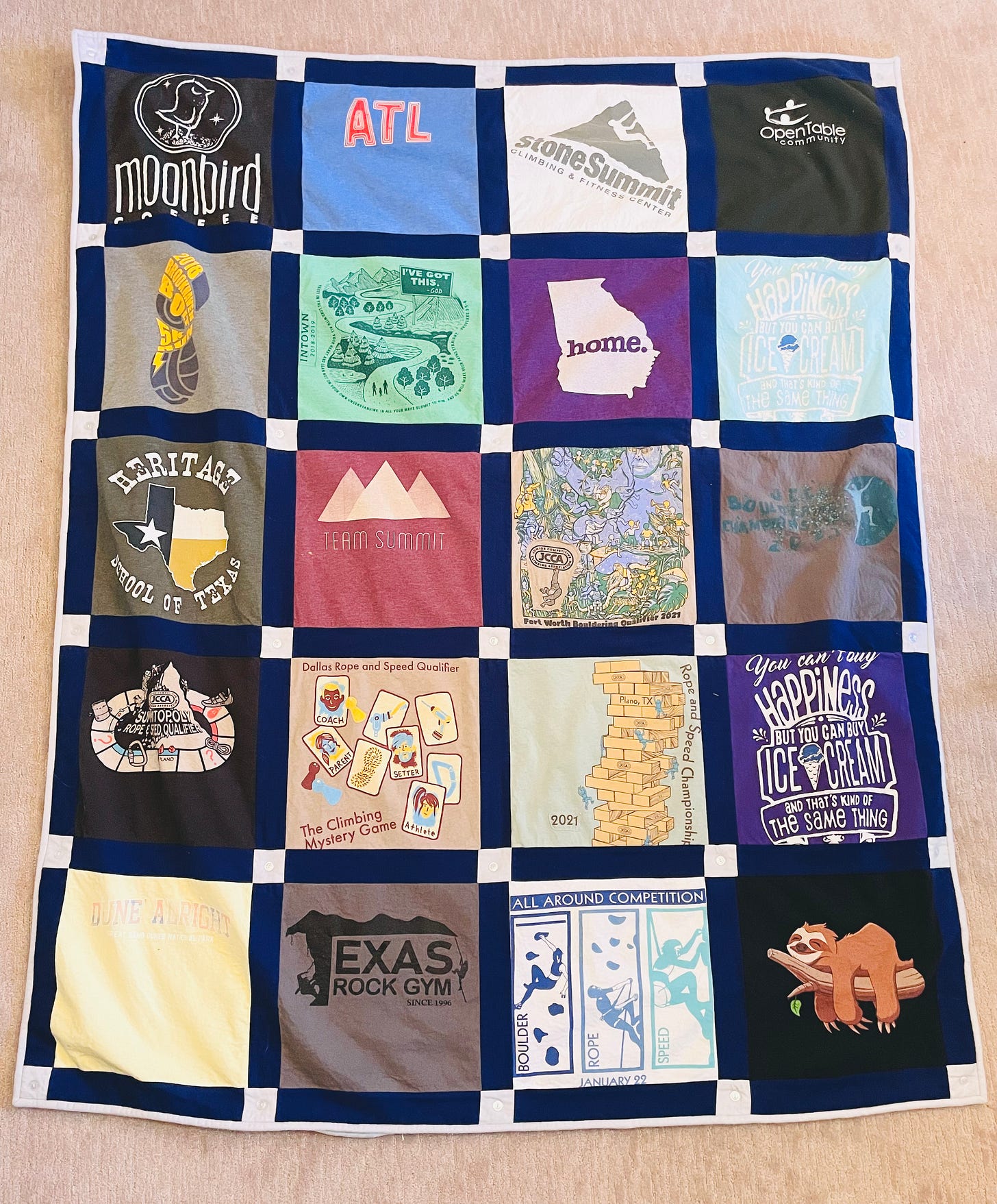 A quilt made from 20 squares of fabric cut from 20 shirts. There are 4 squares in each row, and there are 5 rows. Each square is framed in navy blue sashing
