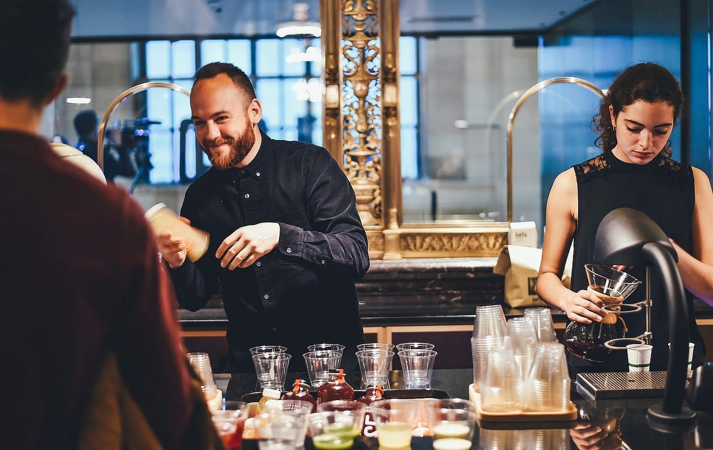 Two bartenders making cocktails at the bar.