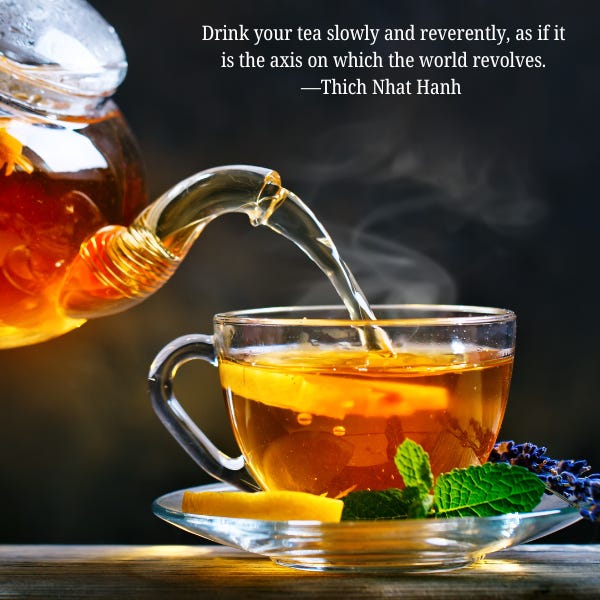 black background with clear glass tea pot pouring hot tea into a clear glass cup with a small green leaf in the foreground and steam coming up off the top of the teacup.