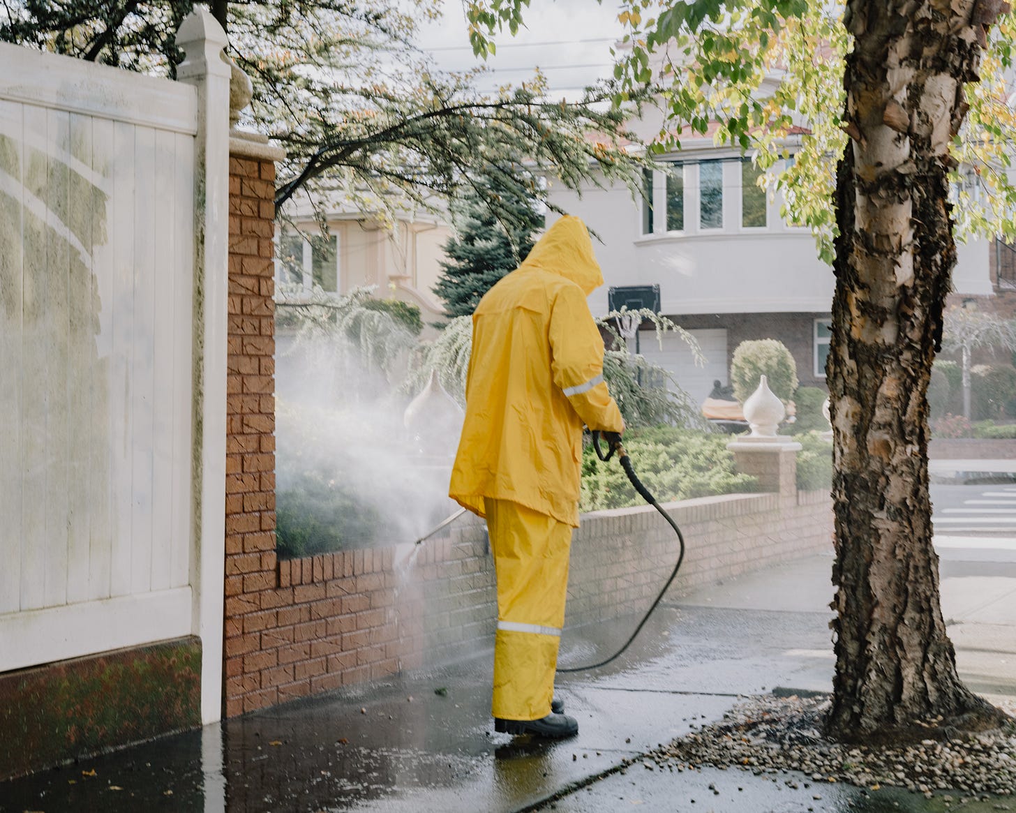Man in yellow rain suit power washing