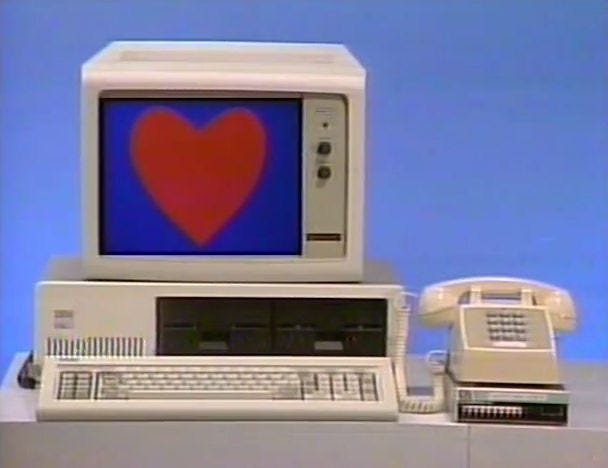 This may contain: an old computer with a heart on the screen and two telephones next to it This may contain: an old computer with a heart on the screen and two telephones next to it