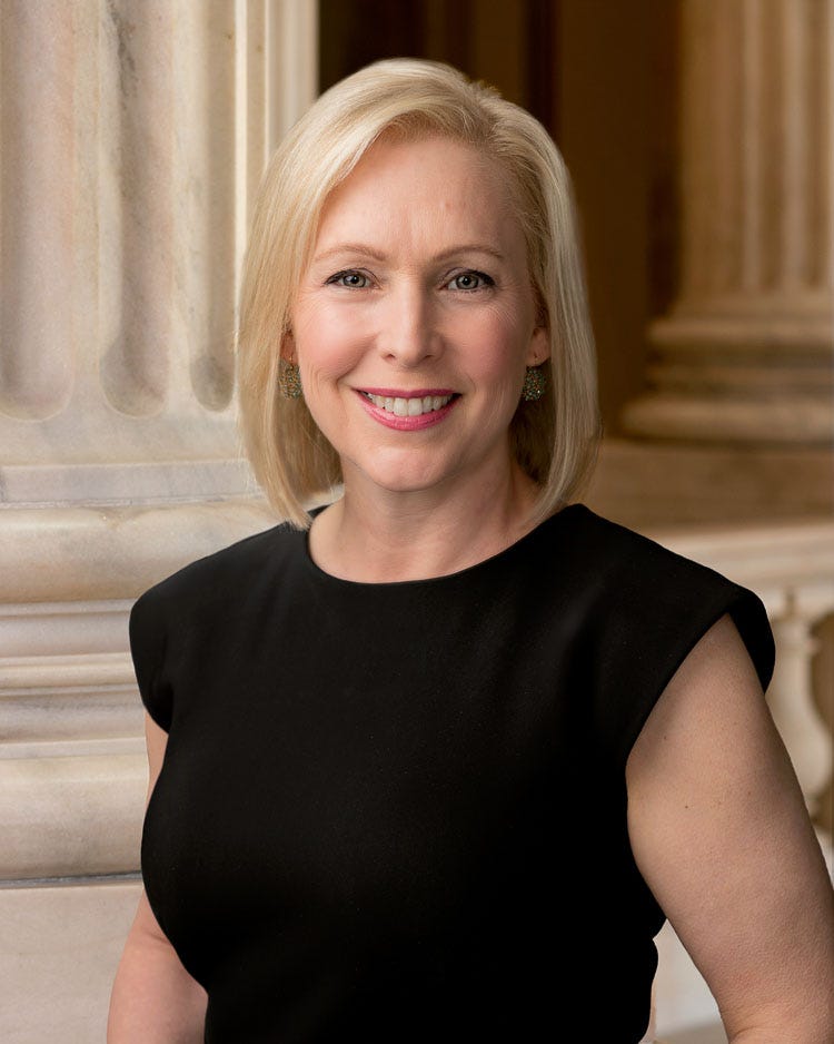 Gillibrand official portrait in front of capital; she is blonde and wearing a black sleeveless blouse
