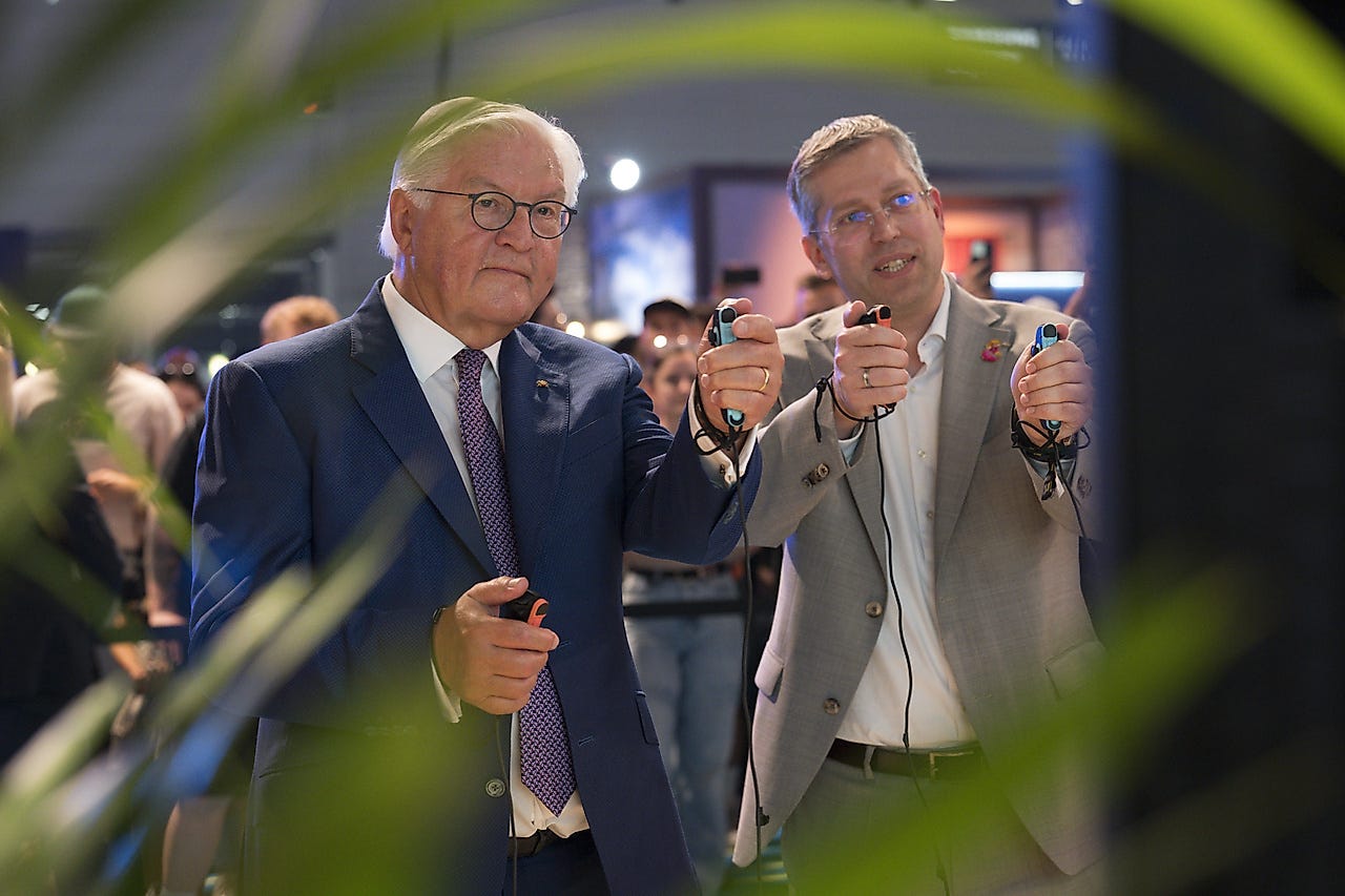 German Federal President Frank-Walter Steinmeier and an accompanying guest test gaming controllers together at gamescom in Cologne.