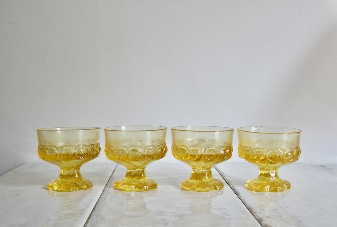 May include: Set of four yellow glass dessert cups with a textured, raised pattern. The cups have a short stem and a wide bowl. May include: Set of four yellow glass dessert cups with a textured, raised pattern. The cups have a short stem and a wide bowl.