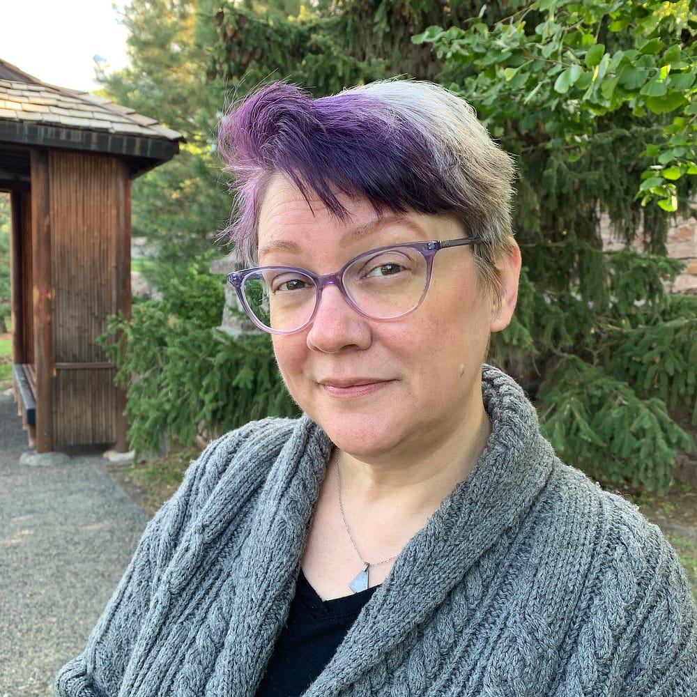 Portrait of Amy Winters-Voss, a spunky lady sporting purple bangs. Is she up to something?
