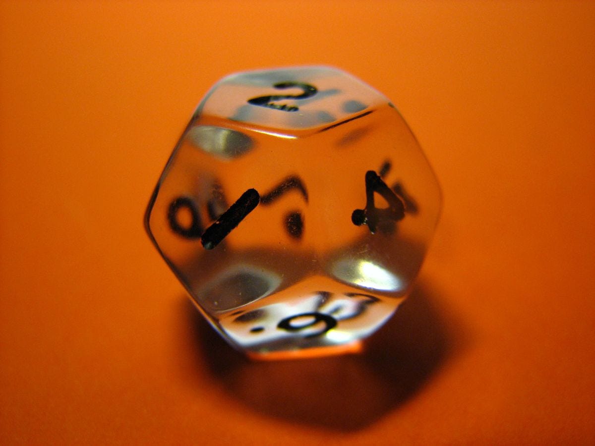The photo of a transparent twelve-sided die on an orange background, reflecting light.