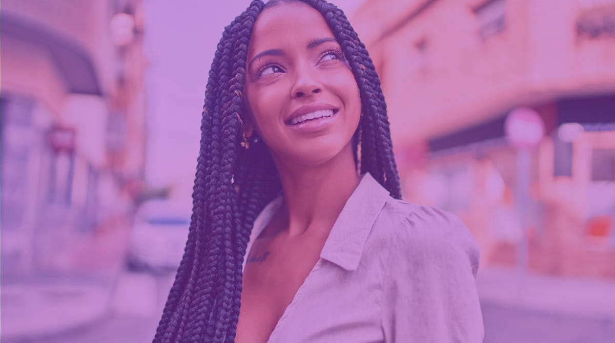 a Black woman with braids smiles and looks up