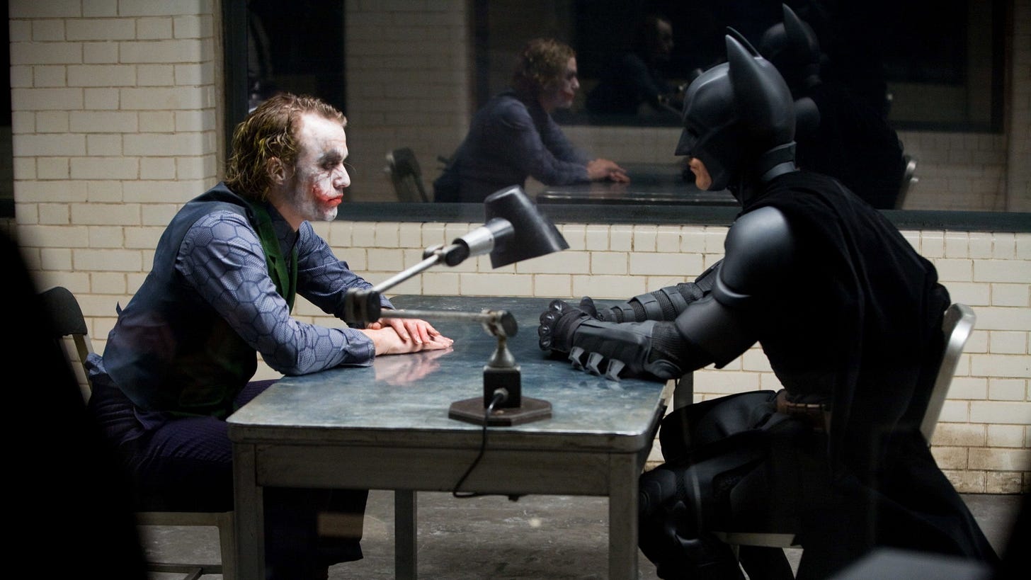 The Dark Knight | Still features Heath Ledger as the Joker sitting across from Christian Bale as Batman, who's interrogating him.