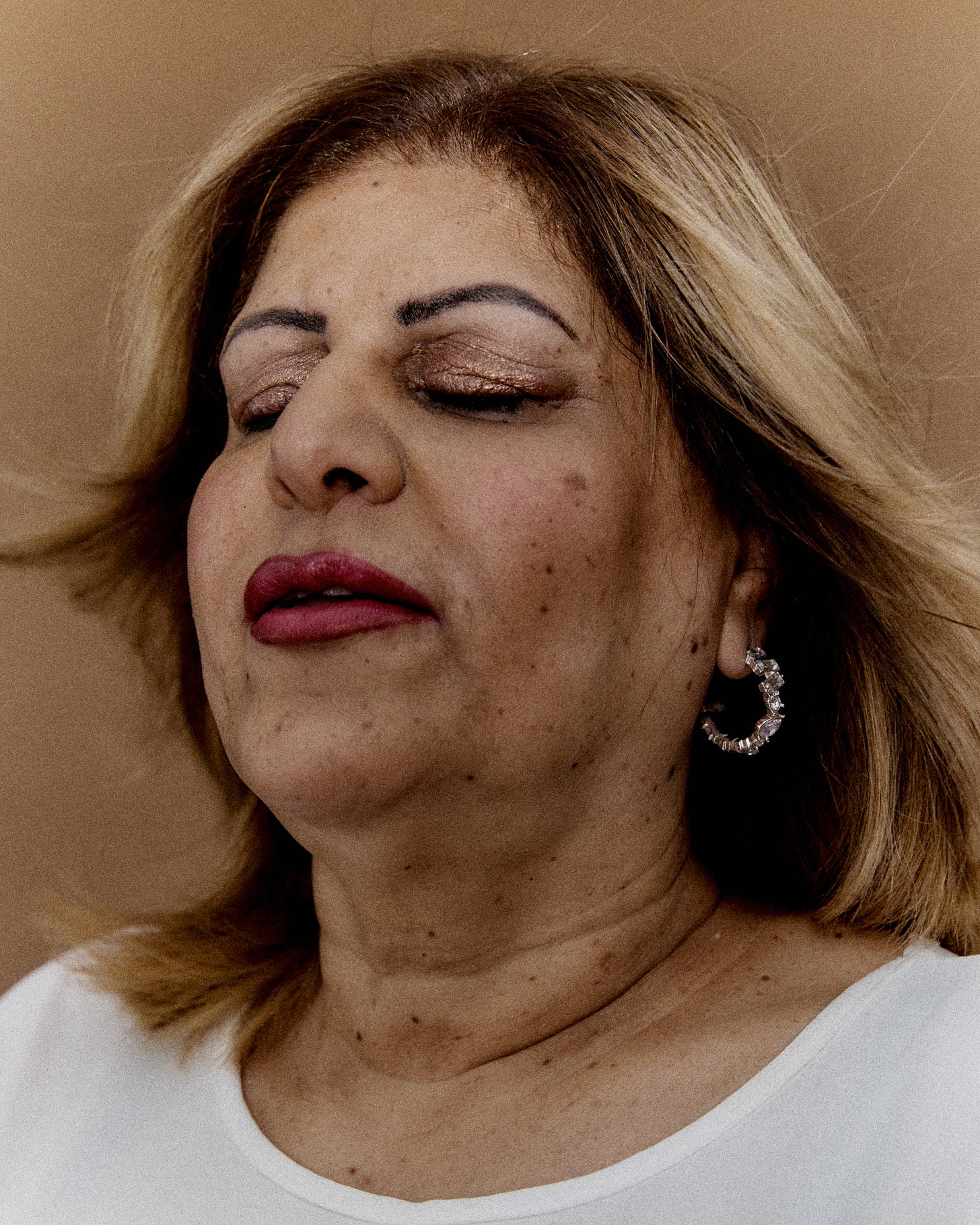 A colour portrait of an adult woman named Fereshteh. She is tilting her head back with her eyes closed as her hair fans out behind her.