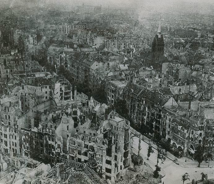Berlin after the collapse of the Third Reich. JFK’s diary described the city in the same terms the image shows: gutted buildings, broken streets, dead bodies, starvation, and a capital reduced to ruins.