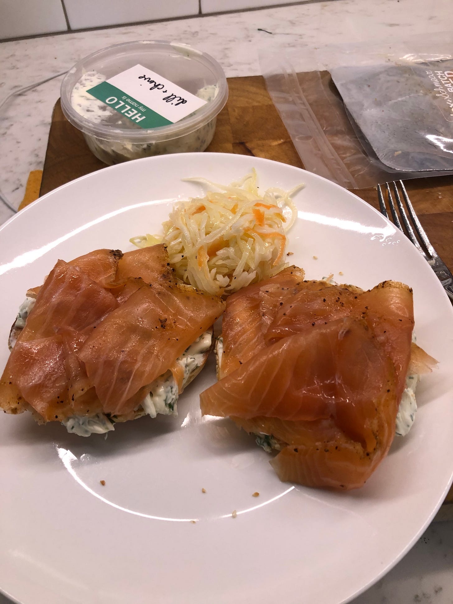 Bagel topped with cream cheese and lox, with cole slaw on the side.