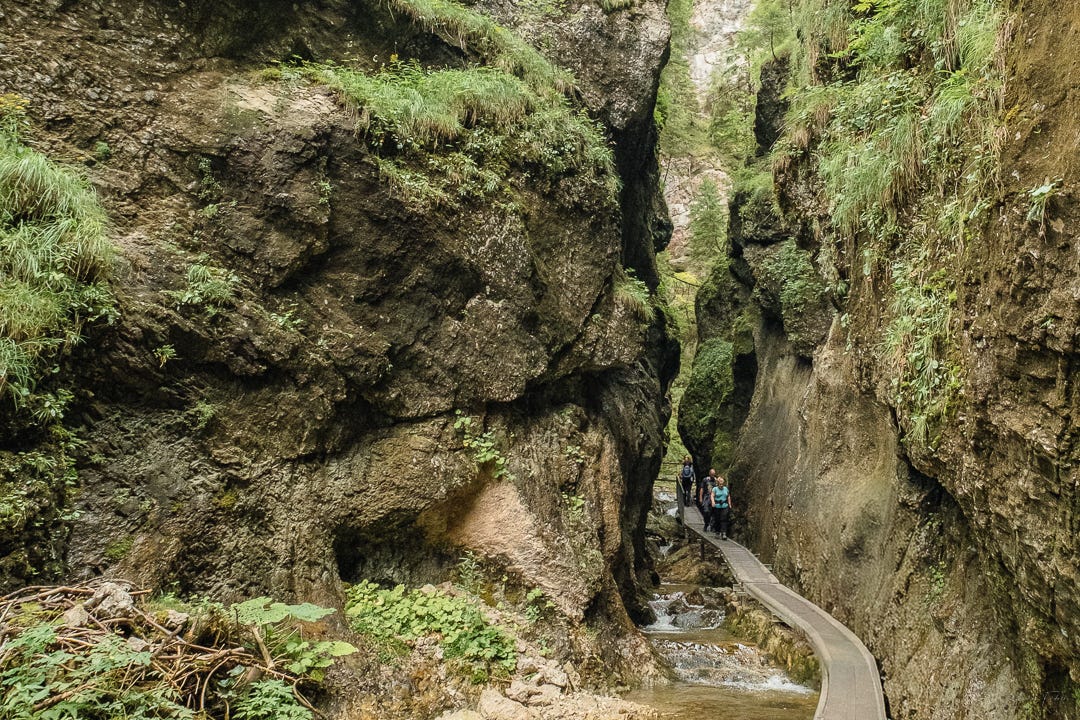People walking on a boardwalk in a gap between two large rock formations