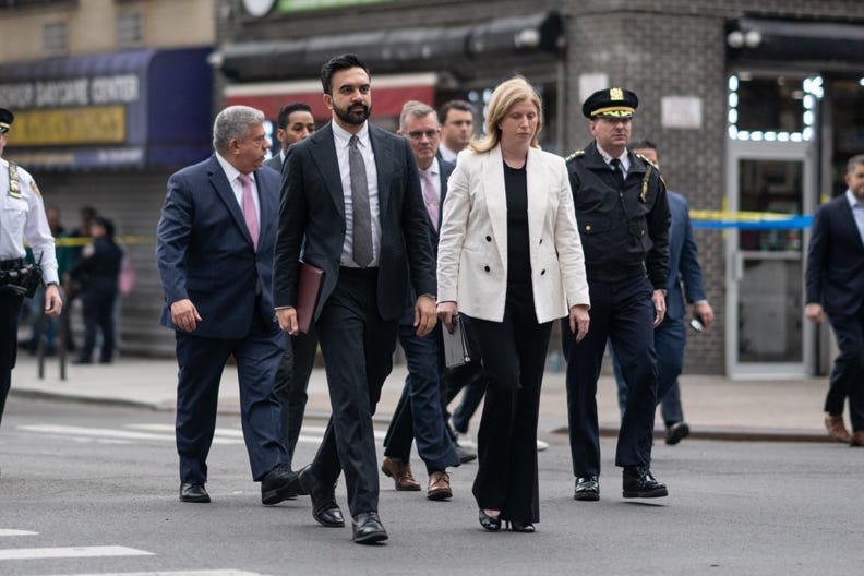 Zohran Mamdani and Jessica Tisch walking with police officers.