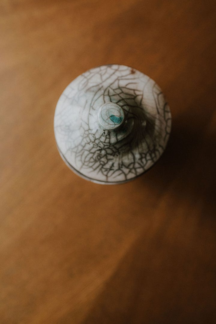 Various ceramic keepsake vessels (urns) of differing sizes and shapes, all raku fired atop a wooden table.