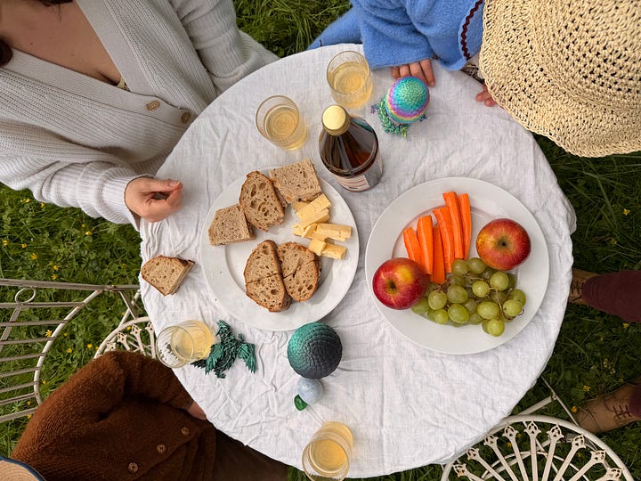 Family lunch at a bistro table outdoors, with sandwiches fruit and passion fruit kombucha