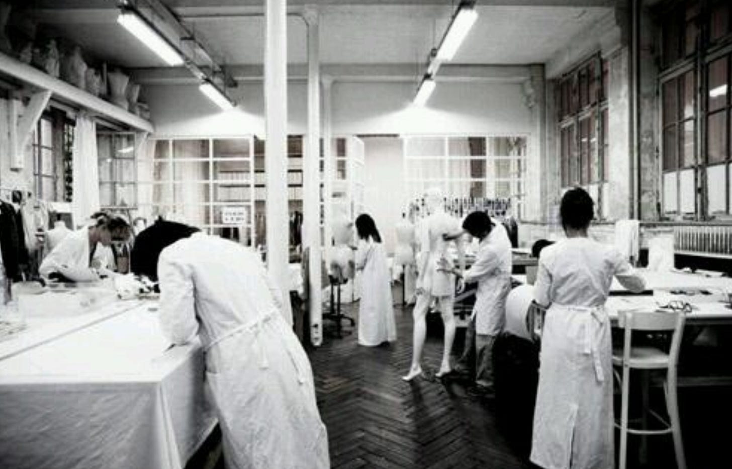 “Photographic and archival imagery of individuals wearing white lab coats as used in the design studio of Maison Martin Margiela. These garments functioned as a symbolic uniform to neutralize hierarchy, promote anonymity, and emphasize collective authorship over individual style. The white coats reflect the psychological and symbolic aspects of enclothed cognition — clothing as a trigger for behavior, identity, and group dynamics.”