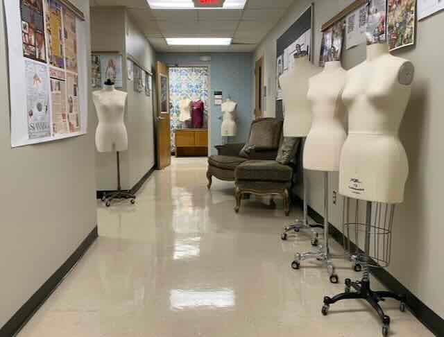 Multiple mannequins in hallway facing floral wallpapered wall outside office space Multiple mannequins in hallway facing floral wallpapered wall outside office space
