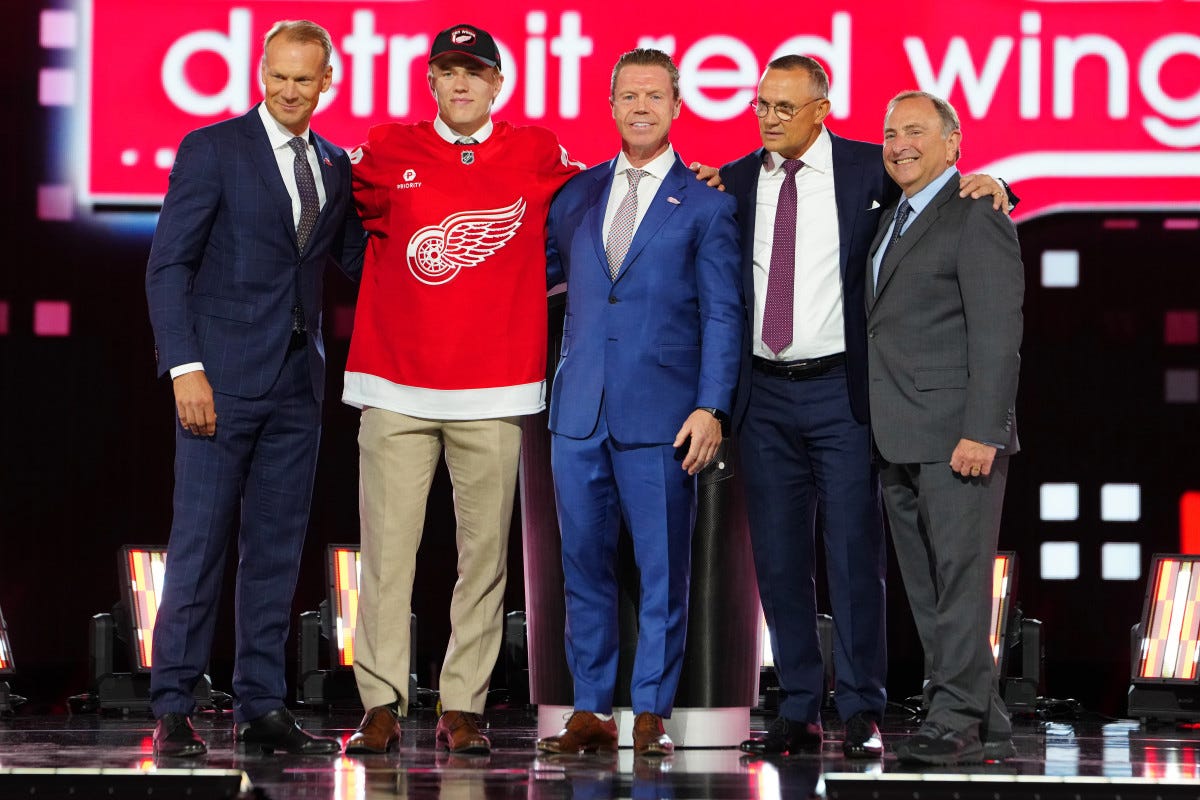 Michael Brandsegg-Nygård poses with Nick Lidstrom, Kris Draper, Steve Yzerman, and Gary Bettman on stage after being drafted by the Detroit Red Wings.