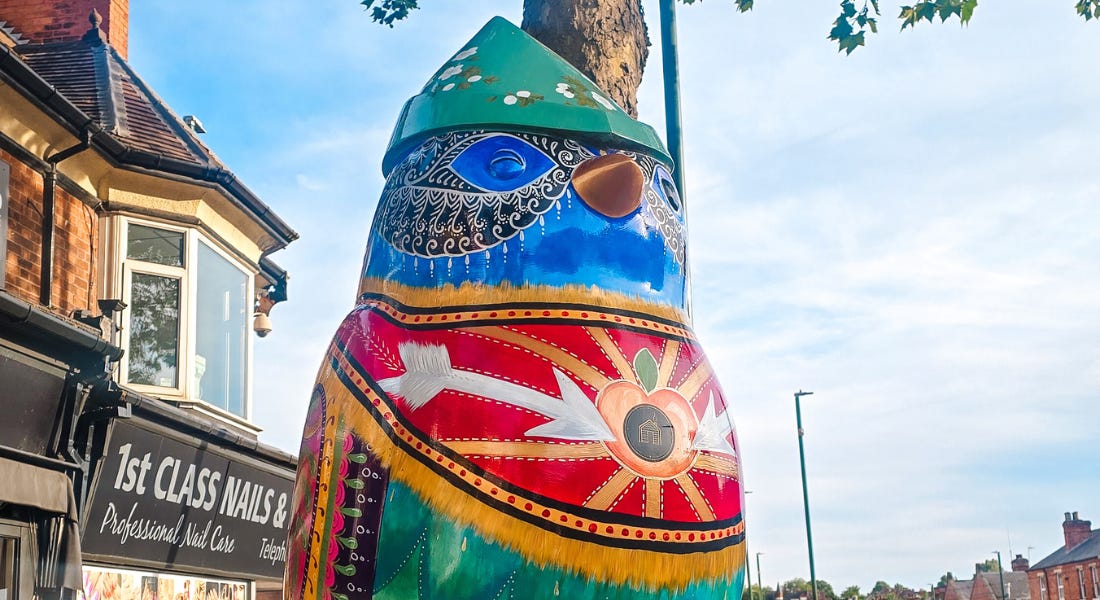 A colourful robin statue with rows of houses either side of it A colourful robin statue with rows of houses either side of it