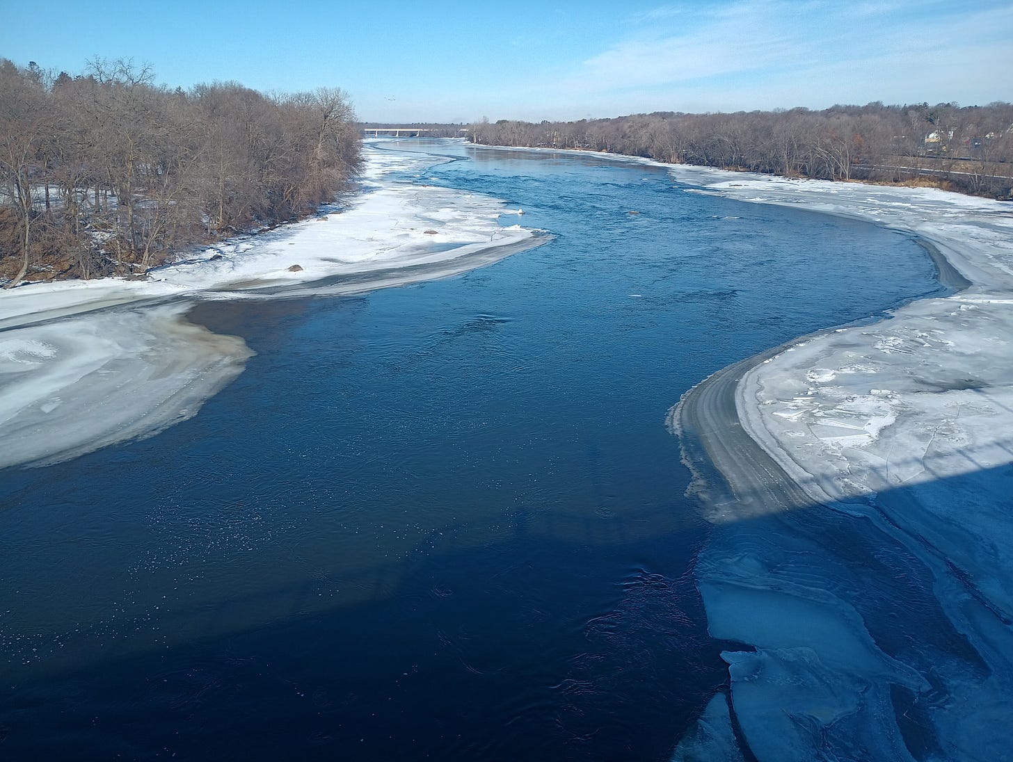 photo of the Mississippi River half covered in ice, from the middle of a bridge