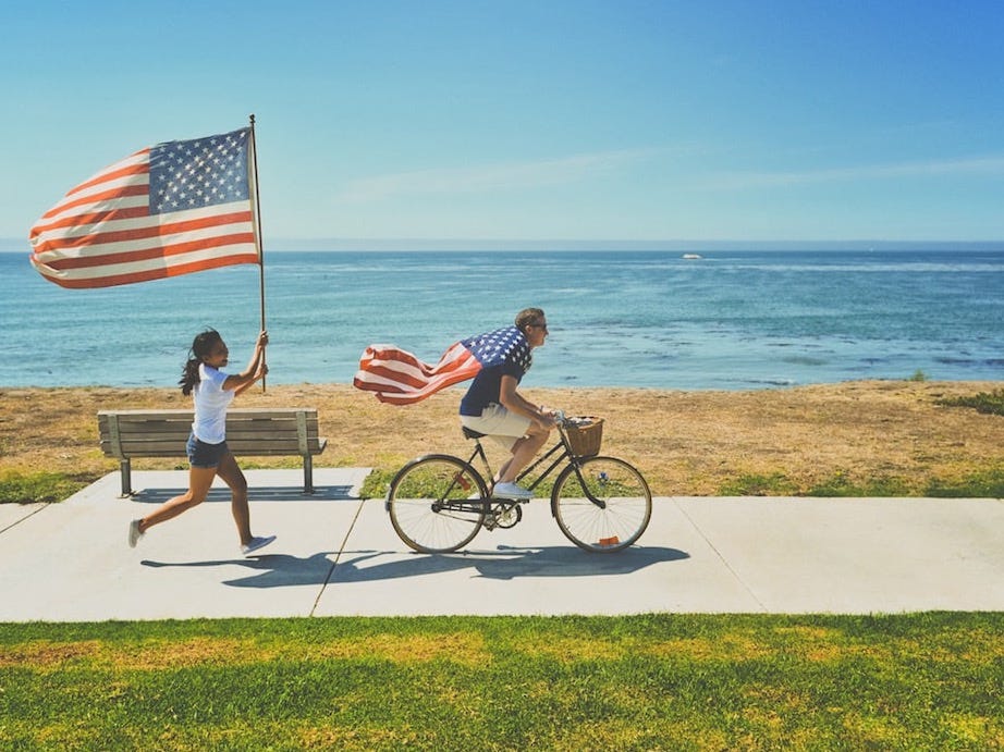 man riding bike and woman running holding flag of USA