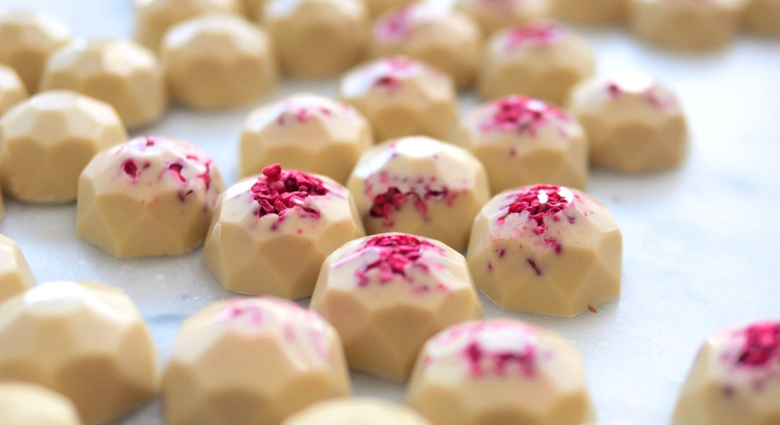 A close-up of white casholate truffles with dried raspberries on top of them A close-up of white casholate truffles with dried raspberries on top of them