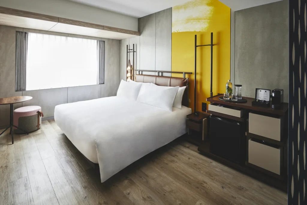 The wheelchair accessible Premier King room at voco Osaka Central, with a king bed, wood-look flooring, and open floor space beside the bed.