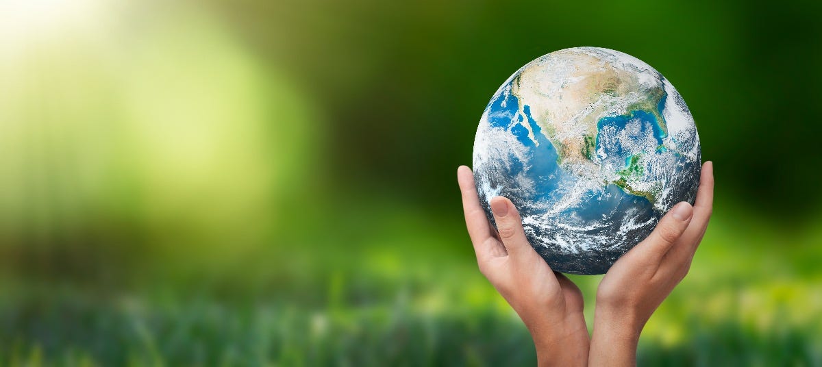 Hands holding planet earth against a green background