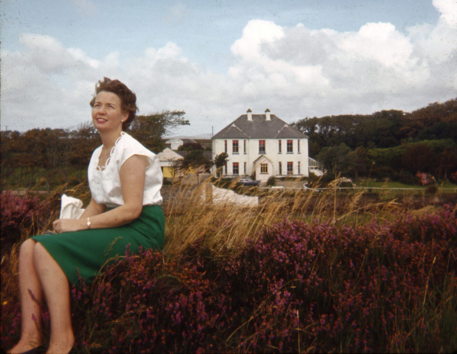 1965 photo of my mother, Úna Little, at age 35, with her parents’ home in County Mayo Ireland in the background. She was a mother of ten children, and died in 1982, aged 52.