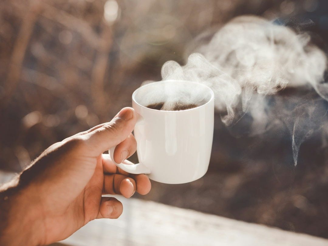 person holding white ceramic cup with hot coffee