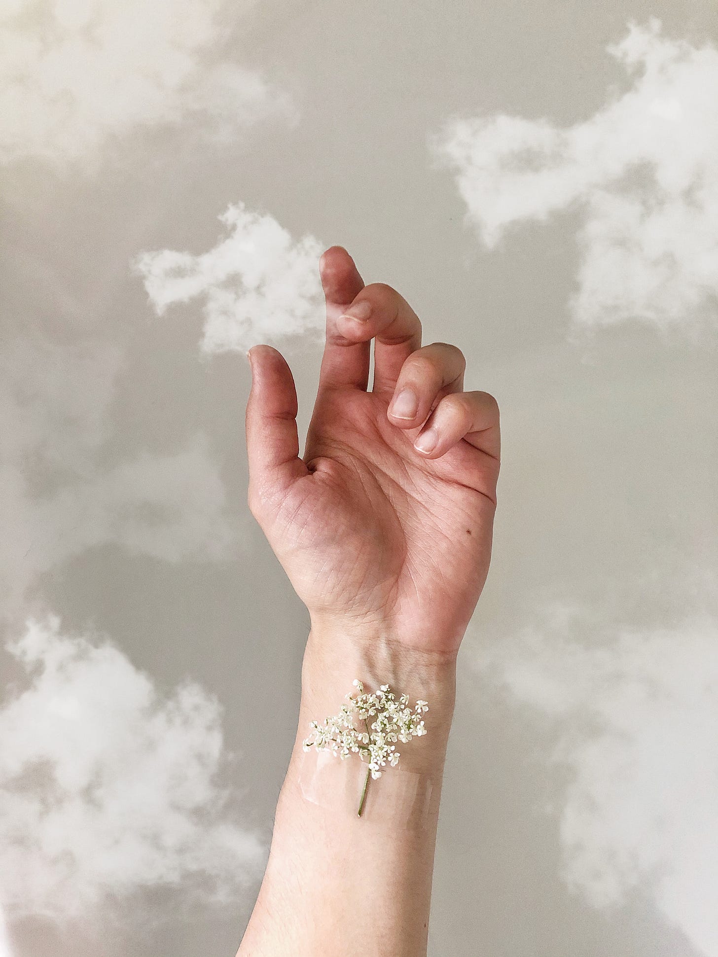 hand holding a cloud with a flower taped to her writst
