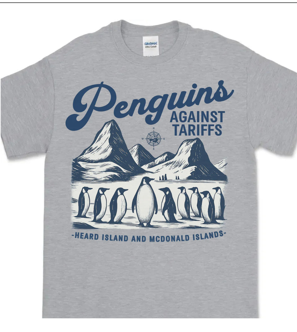 Gray T-shirt with image of penguins and text reading PENGUINS AGAINST TARIFFS | HEARD AND MCDONALD ISLANDS