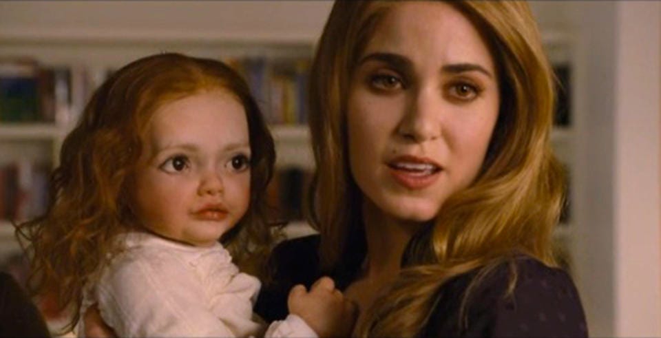 A blonde holding a baby or maybe a toddler (age unclear) with gigantic eyes that look like they were cut and pasted from a bigger picture onto her face. The effect is haunted animatronic doll.