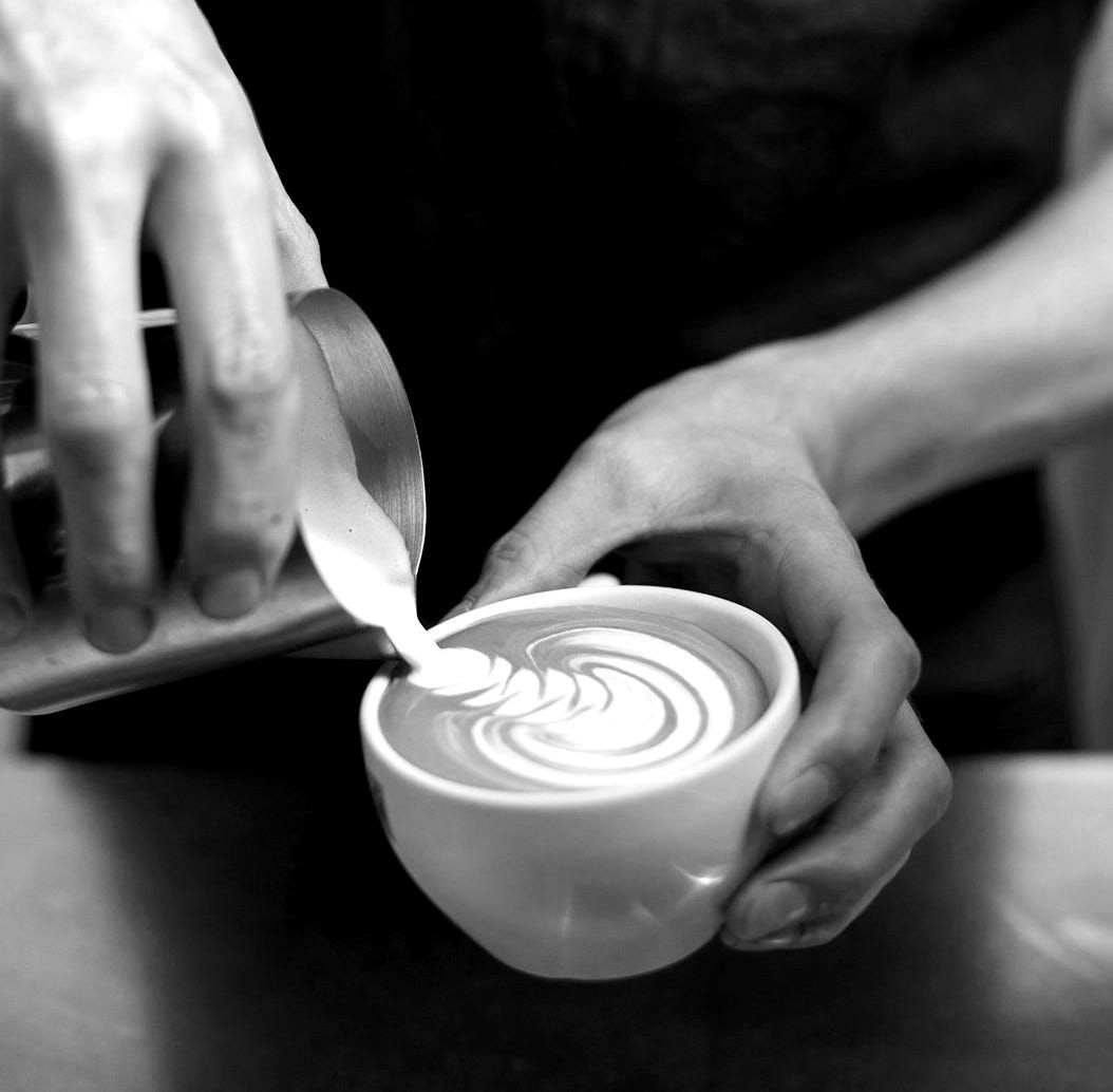 person holding cup making latte art person holding cup making latte art