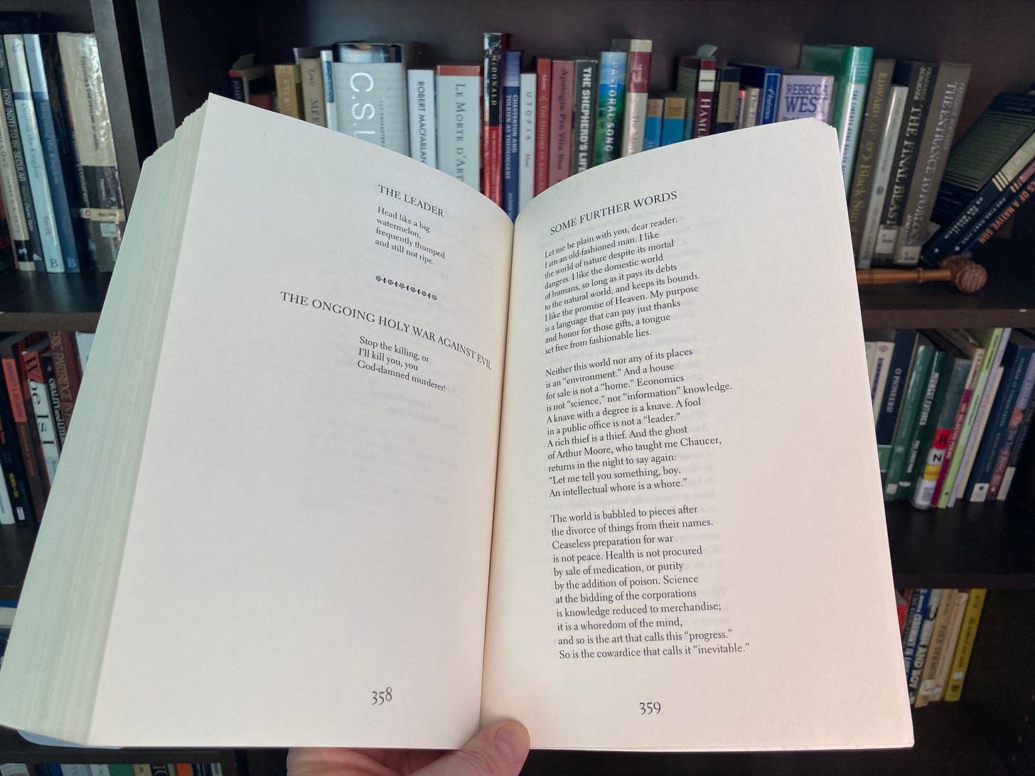 A spread of poems by Wendell Berry held in front of a bookcase; the main poem shown is the beginning of "Some Further Words."