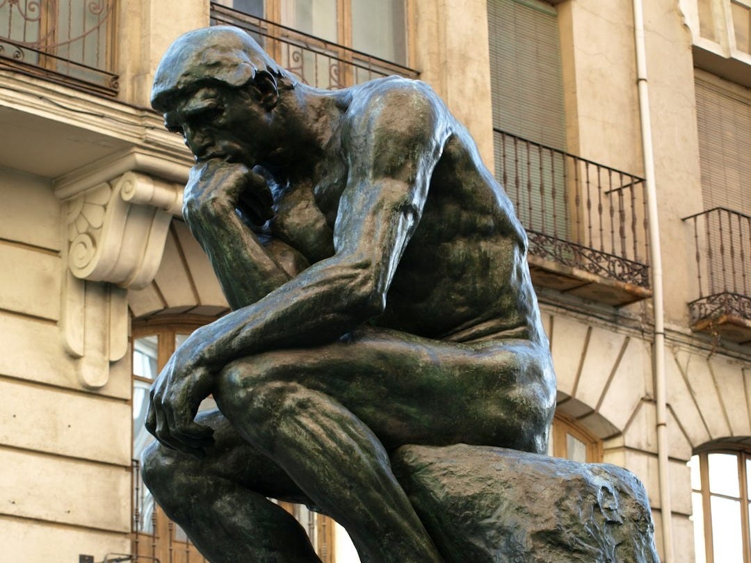 a statue of a man sitting in front of a building