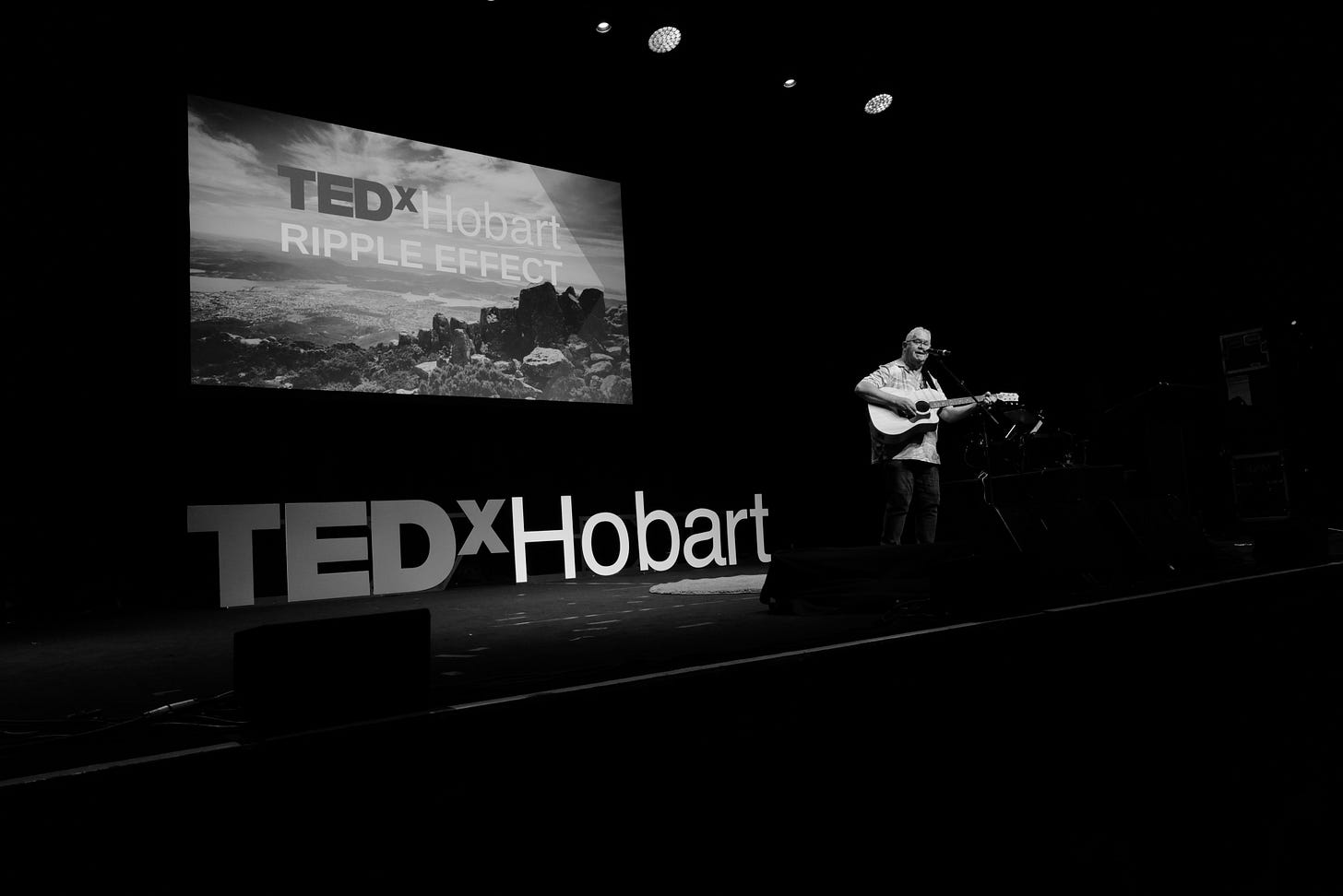 Image from TEDx Hobart - man on stage singing Image from TEDx Hobart - man on stage singing