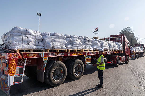 Trucks carrying aid enter Gaza through the Rafah border crossing on July 27, 2025 in Rafah, Egypt. Israel announce a "tactical pause" in fighting in...