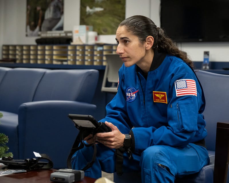 a woman sits on a couch holding a technical device