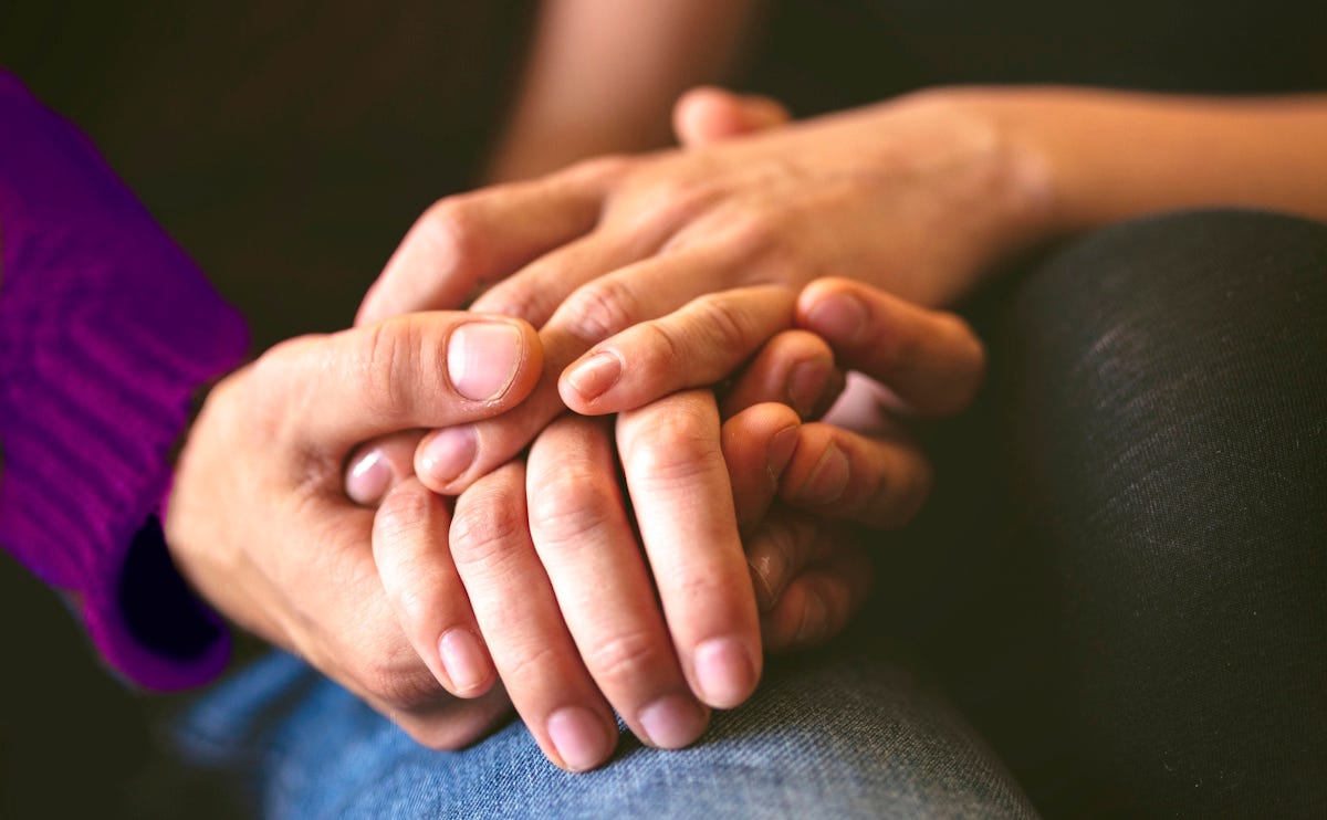 Close-up of two people's hands supportively entwined