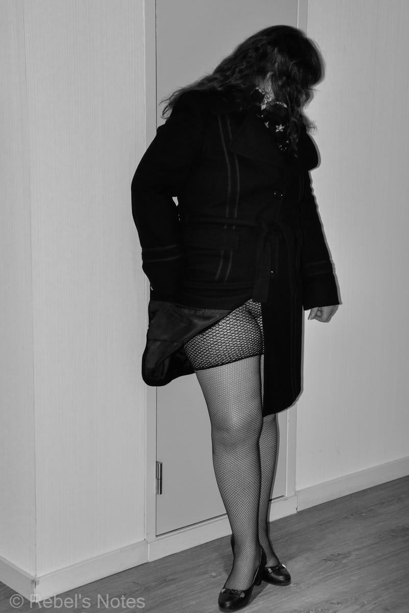 A woman standing against a wall with her coat open showing her fishnet tights A woman standing against a wall with her coat open showing her fishnet tights