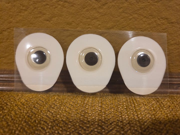 Photos of 3 different types of cardiac electrodes, the sticky pads used on Holter monitors and other devices used to check for arrhythmias. There is one set of 3 foam electrodes with a lot of gel in the center; one “Huggable” children’s electrode that is plastic; and one 3M electrode that is cloth with a small amount of gel in the center.