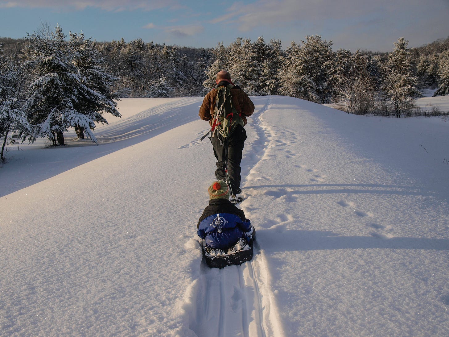 Man pulling boy in sled