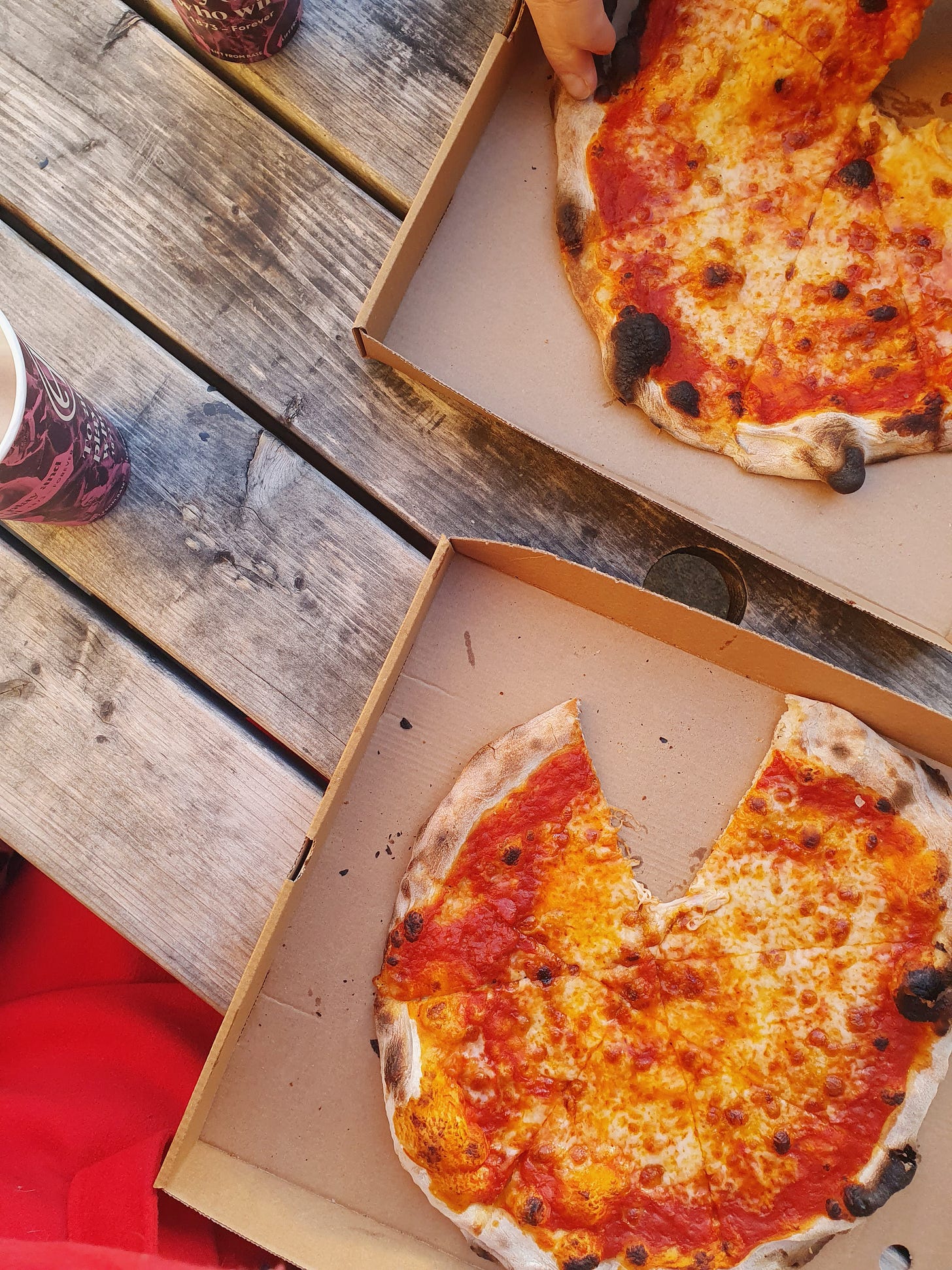 A picture of two pizzas on a table outside.